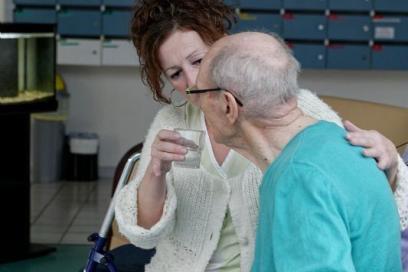 Soignant dans un EHPAD, donnant de l'eau à une personne âgée - Agrandir l'image, fenêtre modale